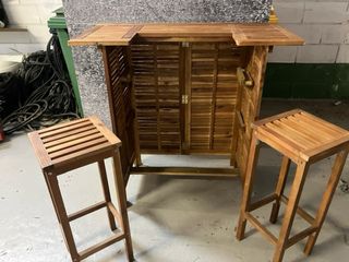 Barra de bar exterior de madera con dos taburetes