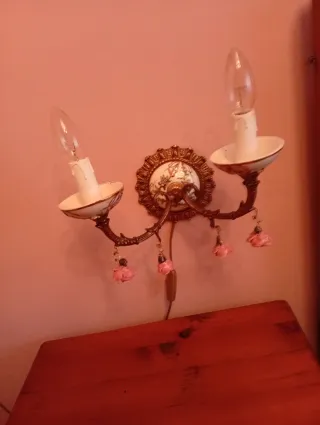 Lámpara de pared dorada con detalles de porcelana.