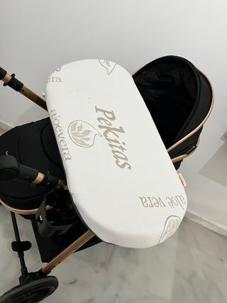 Carrito de bebé negro y dorado con accesorios.