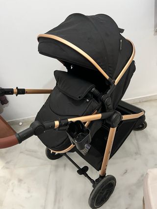 Carrito de bebé negro y dorado con accesorios.