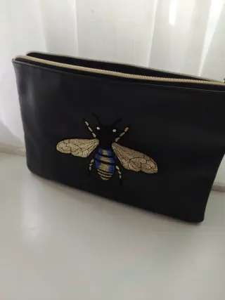 Bolso de mano negro con abeja dorada