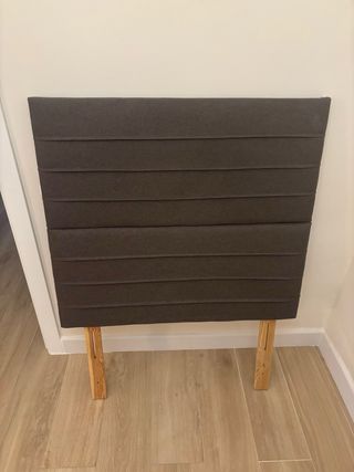 Cabecero de tela gris con patas de madera