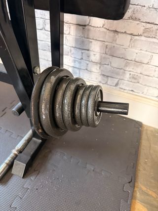 Banco de musculación multifunción y varios discos.