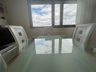 Mesa  de cristal y acero con 6 sillas blancas .