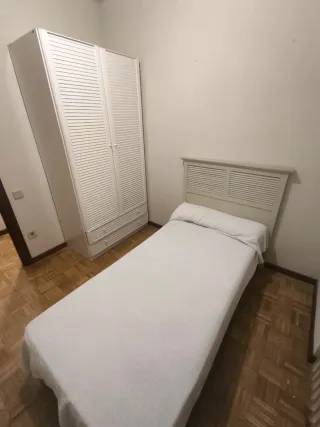 Cama individual blanca con cabecero y armario