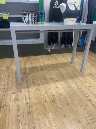 Mesa alta de tienda con perchero.