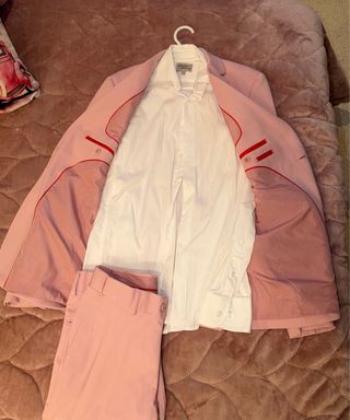 Traje rosa chaqueta y pantalón y camisa blanca.