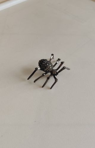Broche de araña metálico con pedrería