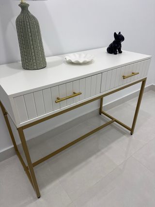 Recibidor blanco y dorado con cajones.