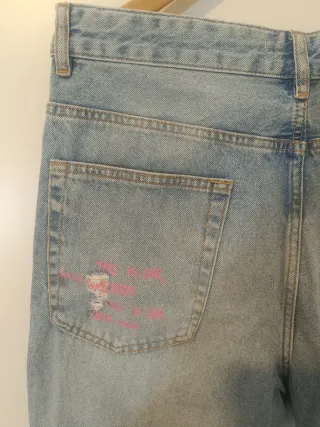 Pantalón vaquero desgastado con texto