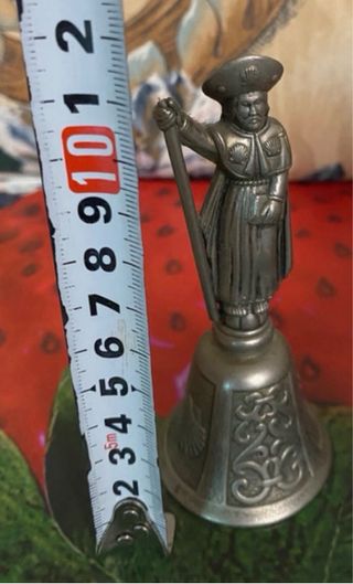 Campana de metal con figura de peregrino
