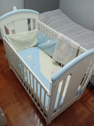 Cuna de madera blanca con detalles azules.