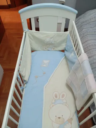 Cuna de madera blanca con detalles azules.