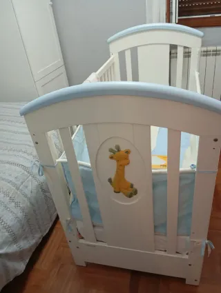 Cuna de madera blanca con detalles azules.