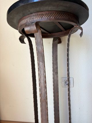 Mesa auxiliar redonda de metal y mármol negro.