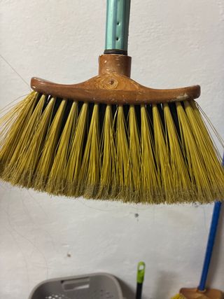 Escoba de cerdas amarillas y mango de madera
