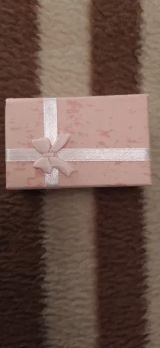 Caja regalo rosa con lazo con joya dentro.
