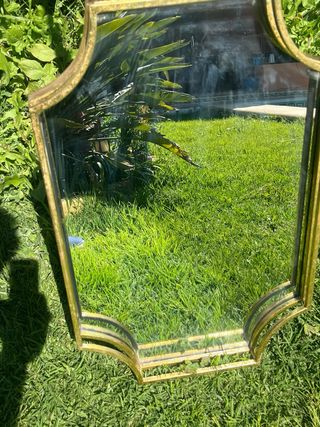 Espejo de metal dorado con marco curvo