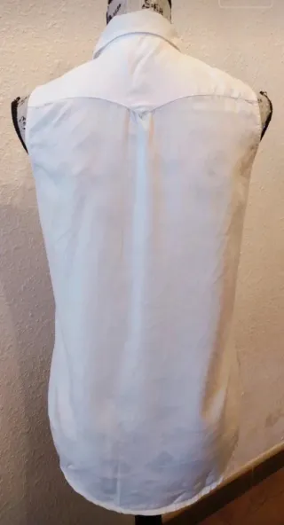 Camisa blanca sin mangas con tachuelas doradas