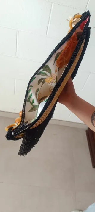 Bolso de mano dorado con flecos negros