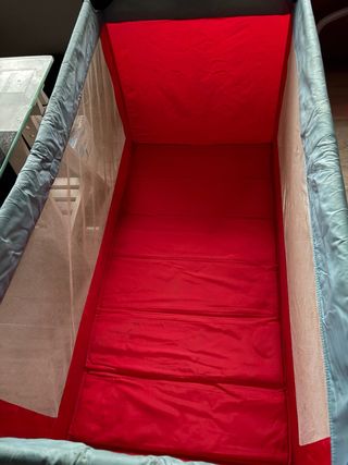 Parque cuna plegable rojo y gris.