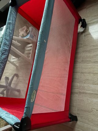 Parque cuna plegable rojo y gris.