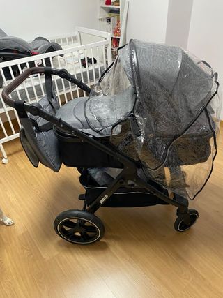 Carrito de bebé gris con funda impermeable