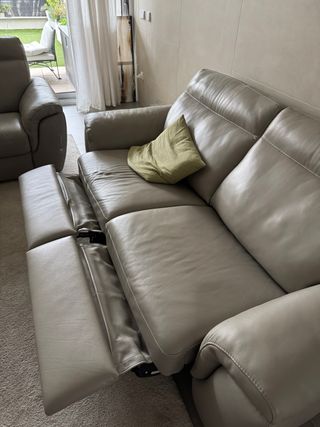 Sofá de piel gris con reposapiés。