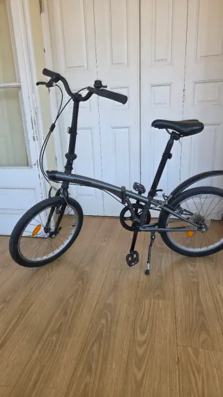 Bicicleta plegable Btwin gris oscuro con candado.