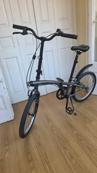 Bicicleta plegable Btwin gris oscuro con candado.