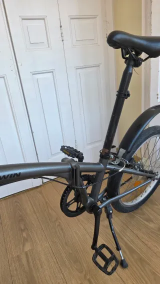 Bicicleta plegable Btwin gris oscuro con candado.