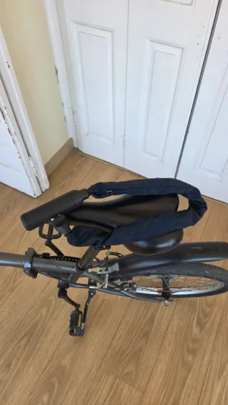 Bicicleta plegable Btwin gris oscuro con candado.