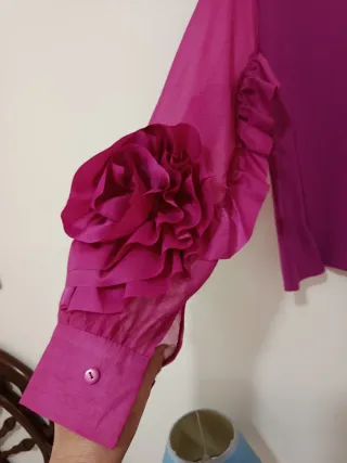 Blusa manga organza volantes fucsia formando flor.