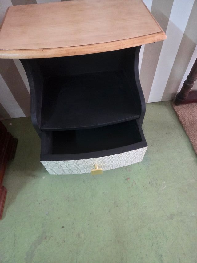 Mesilla de noche negra con detalles dorados.