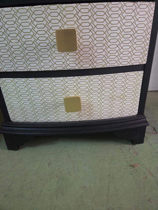 Mesilla de noche negra con detalles dorados.