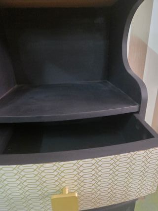 Mesilla de noche negra con detalles dorados.