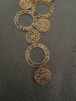 Collana lunga dorata con cerchi e motivi floreali