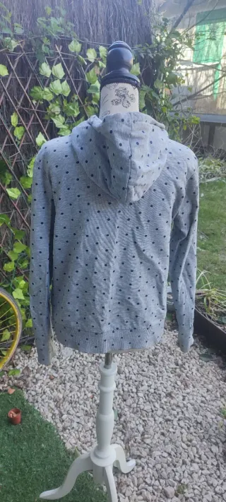 Sudadera gris con puntos,cremallera y capucha.