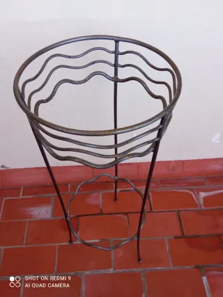 Macetero de pie metálico con plato de cristal.