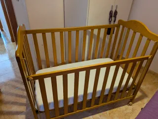 Cuna de madera con colchón y complementos.