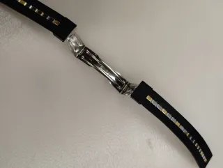 Correa de reloj negra con detalles dorados.