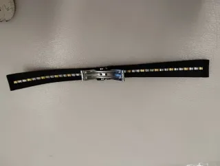 Correa de reloj negra con detalles dorados.