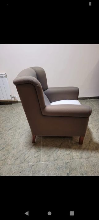 Sillón de tela gris con cojín blanco