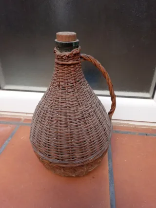 Botella antigua de vidrio con asa y cesta