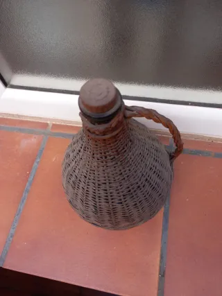 Botella antigua de vidrio con asa y cesta