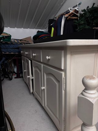 Mesa comedor madera, sillas blancas y cómoda.