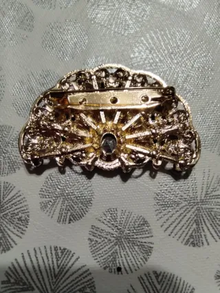 Broche dorado con piedras negras