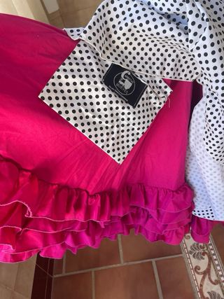 Traje de flamenca blanco, lunar negro y bajo rosa.