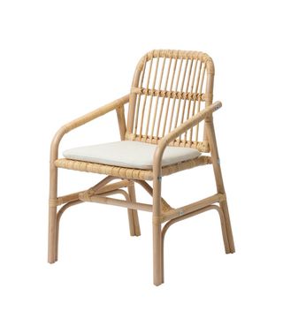 Silla Ikea de ratán con cojín beige.