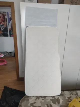 Cuna de bebé blanca con colchón.